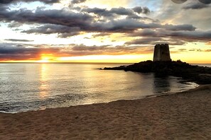 A coastal sunset with a tower on a rocky outcrop.