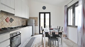 Uma cozinha moderna com área de refeições, um relógio na parede e vista pela porta.