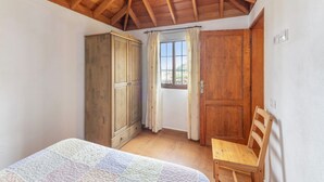 A bedroom with a wooden ceiling, a bed, a wardrobe, a window with curtains, and a chair. - Holiday Home 'La Rehoya' with Sea View, Private Terrace and Wi-Fi (Puntallana)