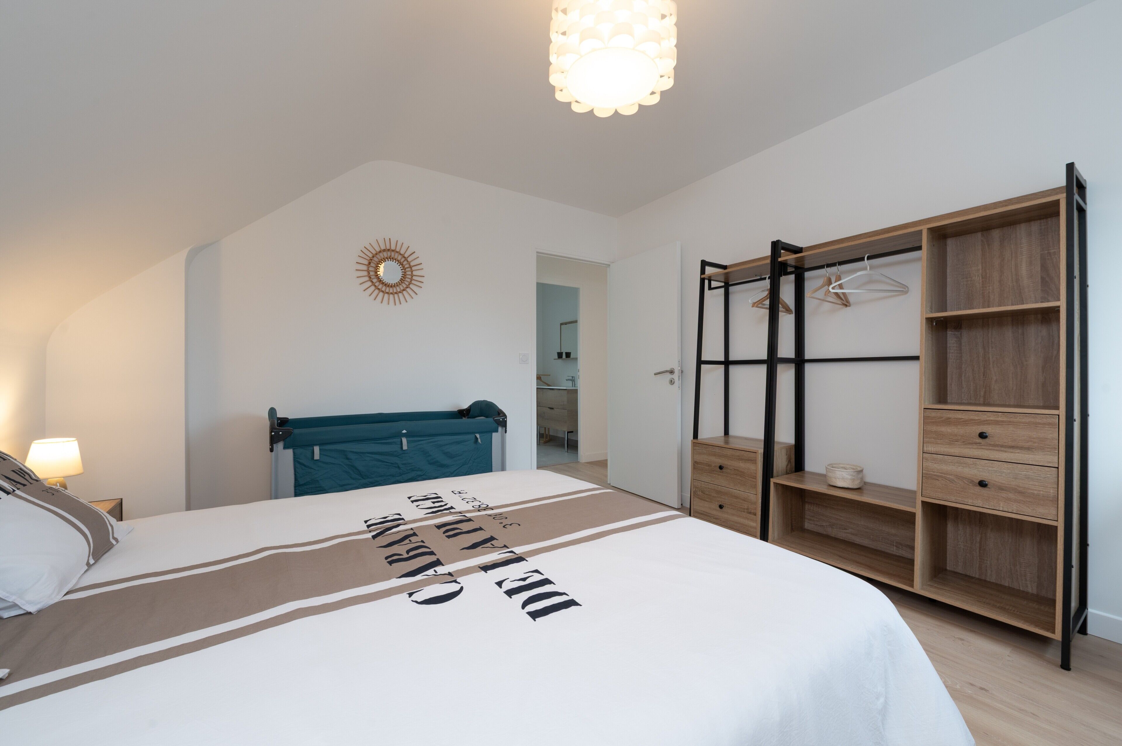 Ein Schlafzimmer mit Bett, Kleiderschrank, Kleiderstange und Deckenleuchte.