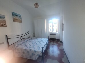 Una camera da letto con un letto, una finestra, un termosifone e una porta.