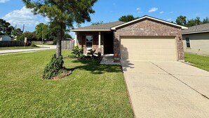 A single-story house with a brick exterior, a front garage, and a well-maintained lawn.