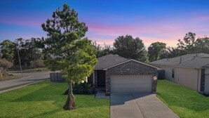 A single-story house with a garage, a well-maintained lawn, and a large tree in the front yard.