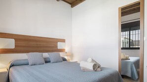 Ein Schlafzimmer mit einem Bett, Nachttischen, einem Spiegel und einem hölzernen Kopfteil.