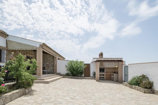 A courtyard with stone flooring, a brick barbecue area, and a small garden with plants and flowers.
