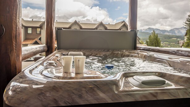 A hot tub with a view of mountains and houses.