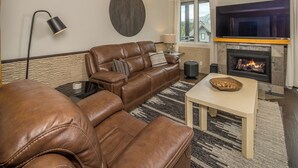 A living room with a leather sofa, a coffee table, a fireplace, and a lamp.