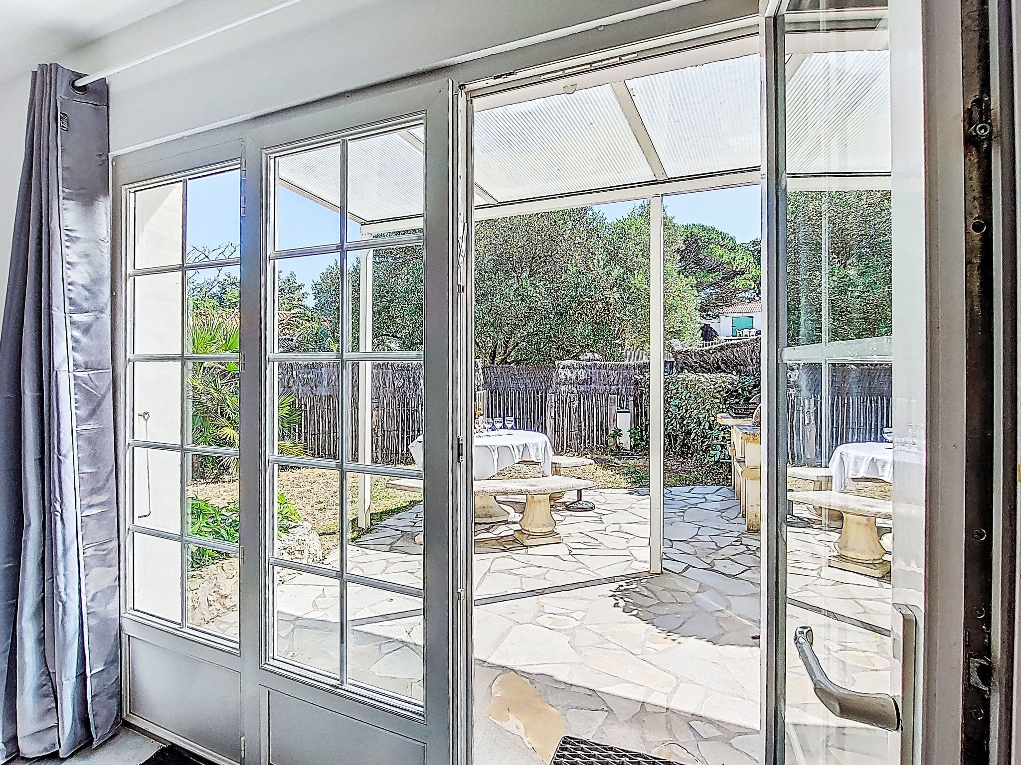 A conservatory with a stone patio and a view of a garden.