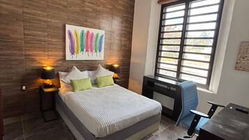 A bedroom with a bed, bedside lamps, a desk, and a chair.