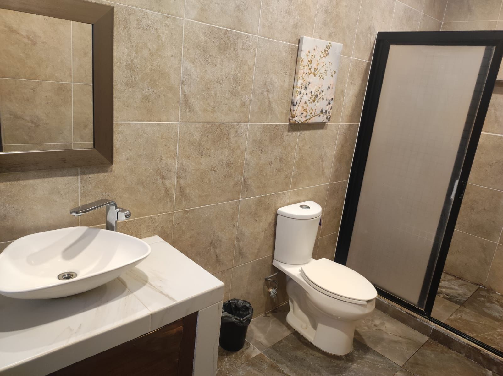 Un baño con lavamanos blanco, inodoro y zona de ducha.