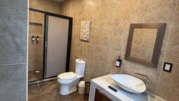 Un baño moderno con inodoro, lavabo y zona de ducha.
