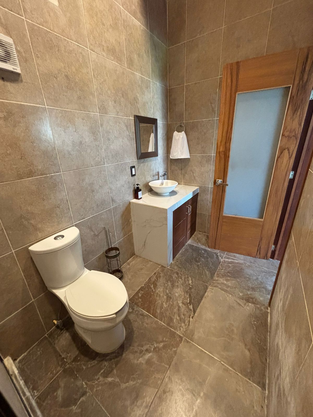 Un baño con inodoro, lavamanos y espejo.