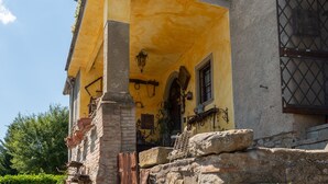 Um edifício amarelo com escadaria de pedra, janela com grades de metal e parede de pedra.