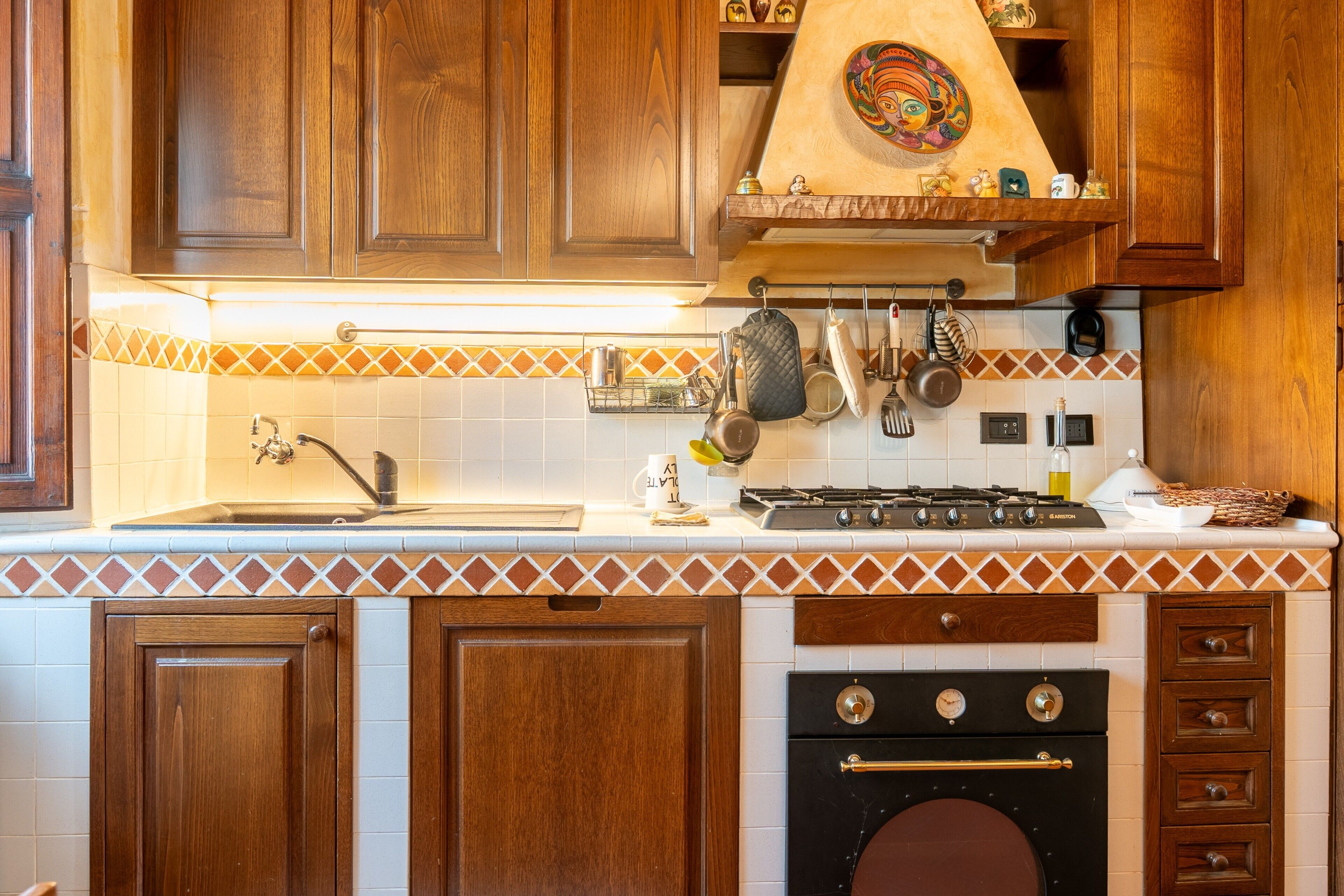 Una cocina con armarios de madera, estufa y salpicadero de azulejos.