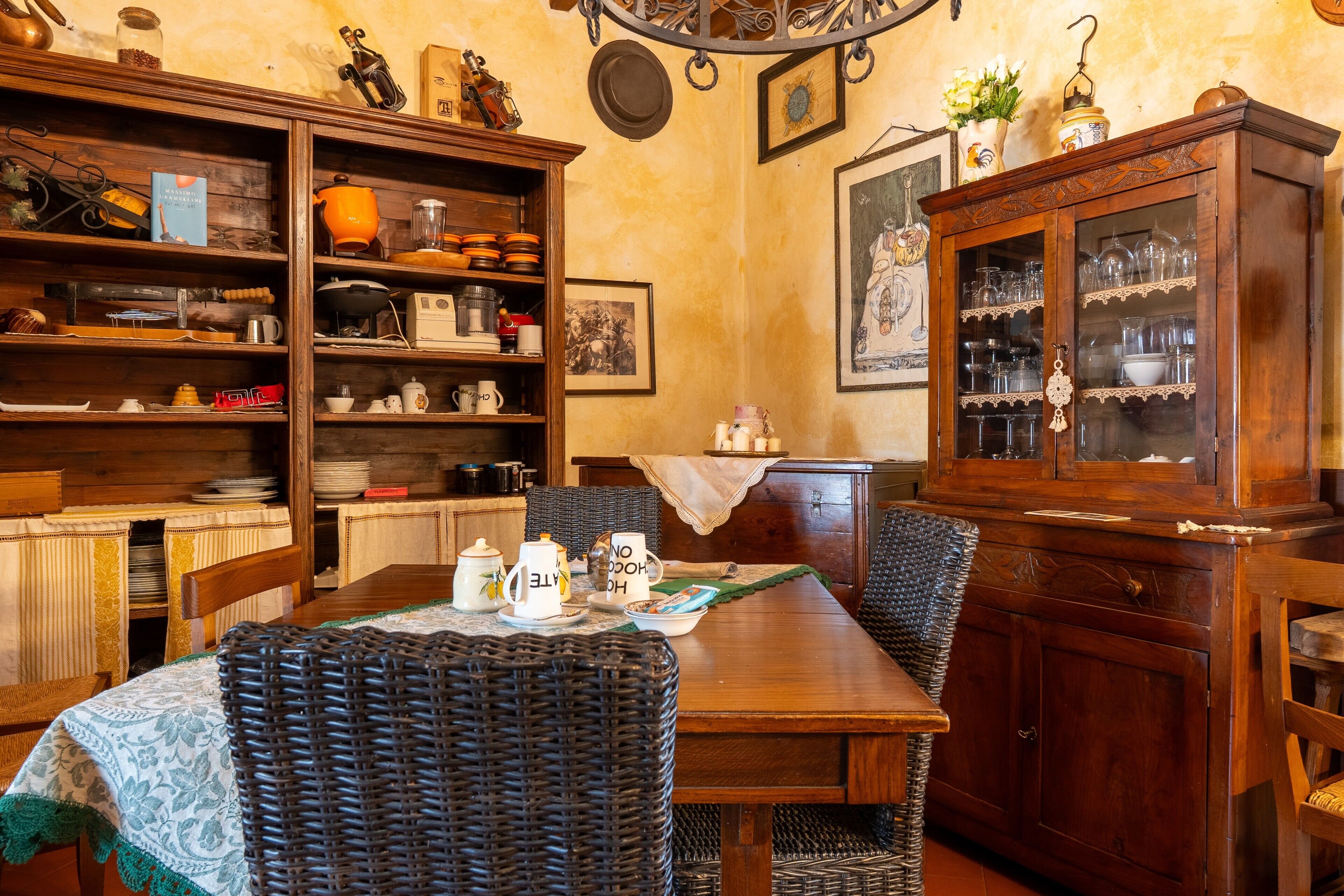 Un coin repas avec une table en bois, des chaises en osier et un buffet aux portes vitrées.
