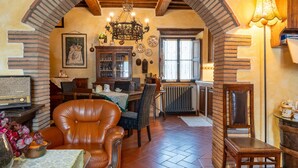 A cozy dining area with a brick archway, a chandelier, and a dining table set with chairs.