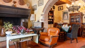 A cozy room with a fireplace, a dining area, and a comfortable chair.