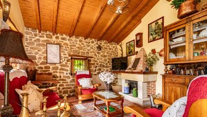 Un interior rústico con paredes de piedra, muebles de madera, una chimenea y un televisor.