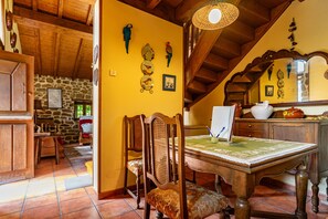 Un coin repas rustique avec une table en bois, des chaises et un mur de pierres en arrière-plan.