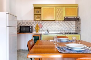 Una cocina compacta con microondas, estufa y armarios amarillos.
