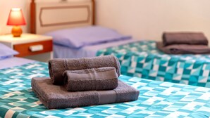A hotel room with a bed, a nightstand, a lamp, and a checkered bedspread.