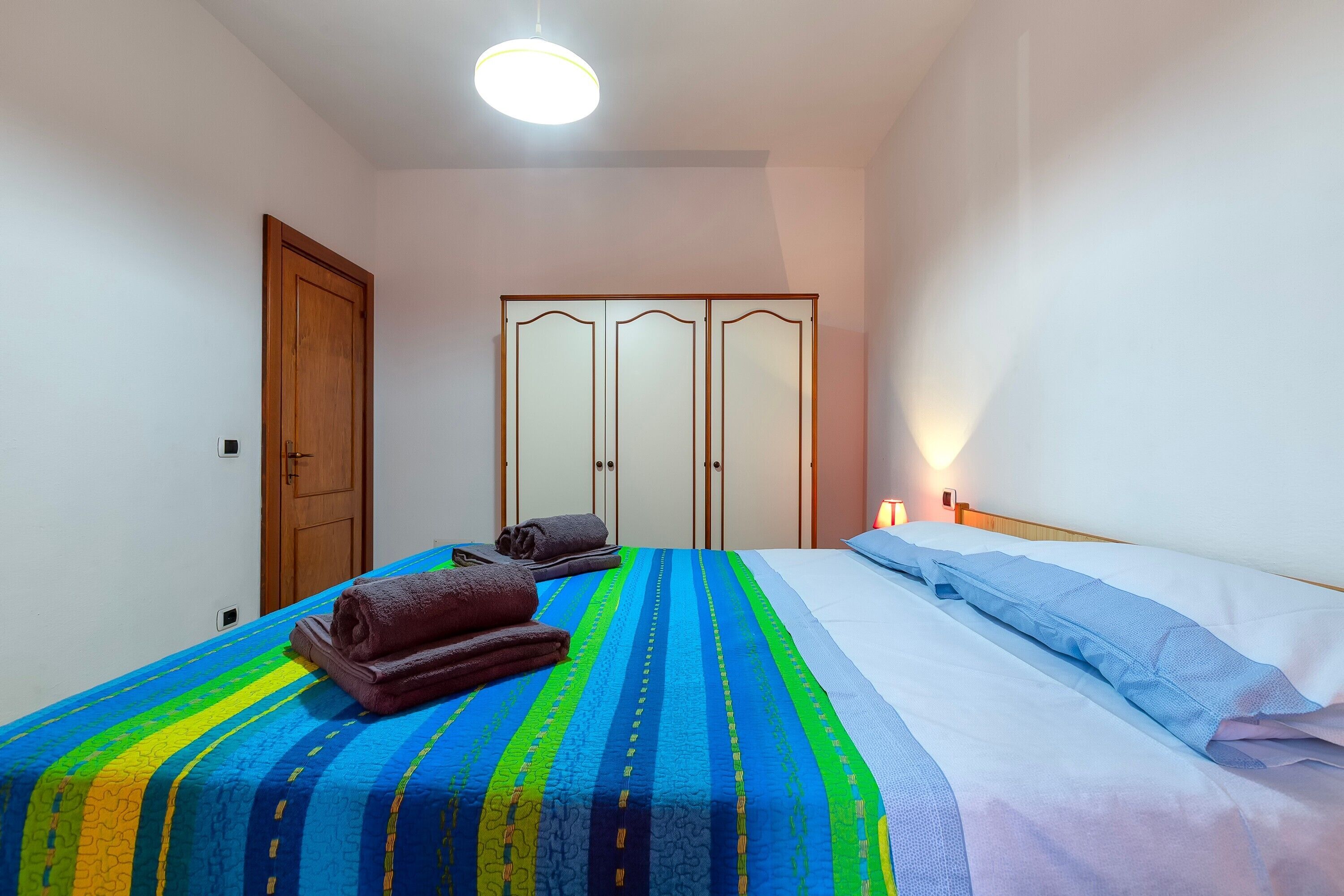 A bedroom with a bed, a wardrobe, and a nightstand.