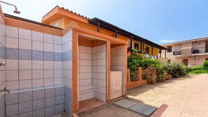 A tiled outdoor shower area, a mattress, and a building with balconies.