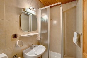 A bathroom with a sink, mirror, and shower.
