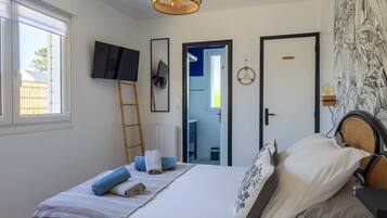 Un dormitorio con una cama, televisión, escalera, puerta y pared con estampado floral.