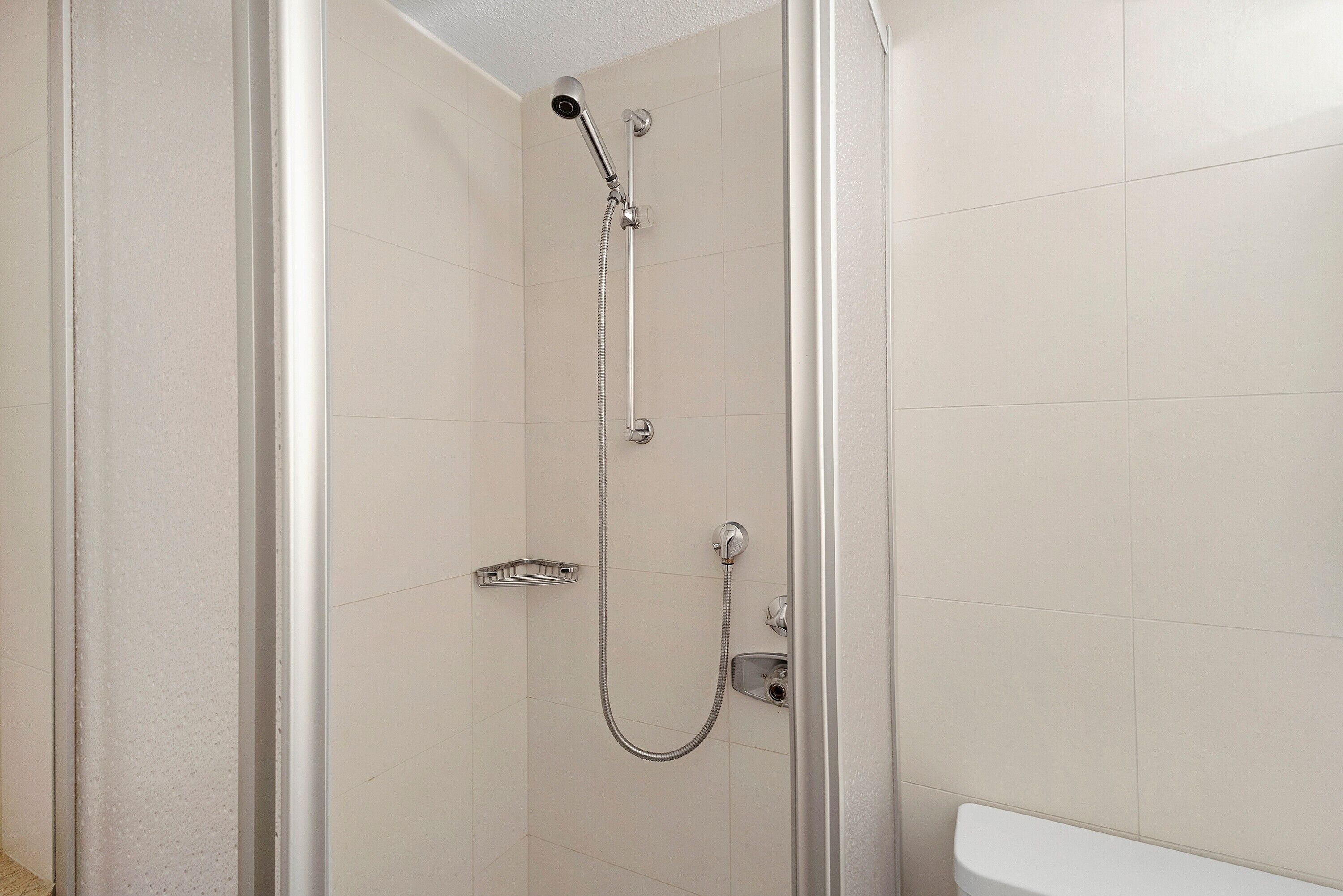Une douche équipée d’un pommeau de douche à main, d’un robinet mural et d’un robinet fixé au sol.