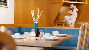 A dining table set with white plates, glasses, and a vase with white flowers.