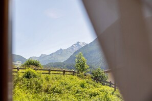 A mountain landscape with a wooden fence and a building in the foreground.