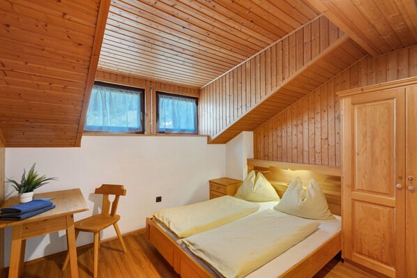 A wooden-paneled room with a bed, a desk, a chair, and a window. - Room 'Pension Waldheim  7' with Mountain View, Shared Garden and Wi-Fi (Ahrntal)