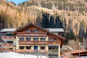 A multi-story building with balconies, labeled 'Pension Waldheim,' surrounded by a snowy landscape and forested hills. - Room 'Pension Waldheim  7' with Mountain View, Shared Garden and Wi-Fi (Ahrntal)