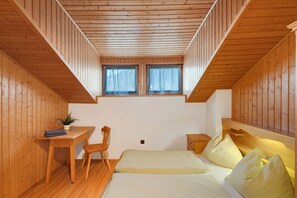 A wooden-paneled room with a bed, a desk, a chair, and two windows. - Room 'Pension Waldheim  7' with Mountain View, Shared Garden and Wi-Fi (Ahrntal)