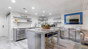 A modern kitchen with a central island, stainless steel appliances, and a bar area with stools.