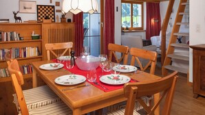 A dining area with a wooden table set for four, surrounded by wooden chairs. There is a bookshelf to the left and a staircase to the right. - La Siala Apt.56A by Interhome (Falera)
