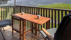 A wooden deck with a table and chairs, overlooking a mountainous landscape. - La Siala Apt.56A by Interhome (Falera)