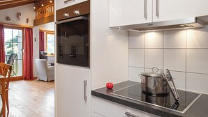 A modern kitchen with white cabinets, a black oven, and a stainless steel pot on an induction cooktop. - La Siala Apt.56A by Interhome (Falera)