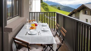 A balcony with a table set for two, overlooking a mountainous landscape. - La Siala Apt.17 by Interhome (Falera)