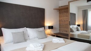 A hotel room with a large bed, a wooden headboard, a nightstand with a lamp, and a mirror reflecting the bed. - La Siala Apt.17 by Interhome (Falera)