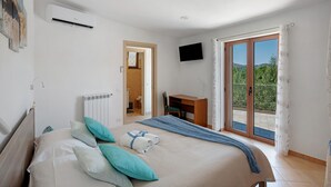 Une chambre avec un lit, un bureau, une télévision et un balcon offrant une vue.