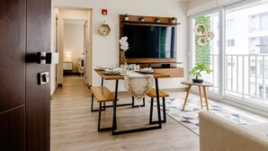 A modern living room with a dining table, benches, a TV, and a balcony with a view.