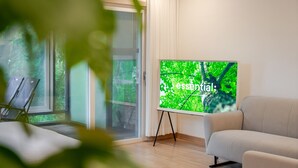 A modern room with a large window, a sofa, and a screen displaying a nature scene. - Chuncheon Haven Forest Pension (Chuncheon)