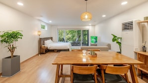 A modern hotel room with a wooden dining table, two chairs, a bed, a TV, and a large window offering a view of the outdoors. - Chuncheon Haven Forest Pension (Chuncheon)