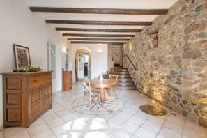 A dining area with a stone wall, wooden beams, and a tiled floor.