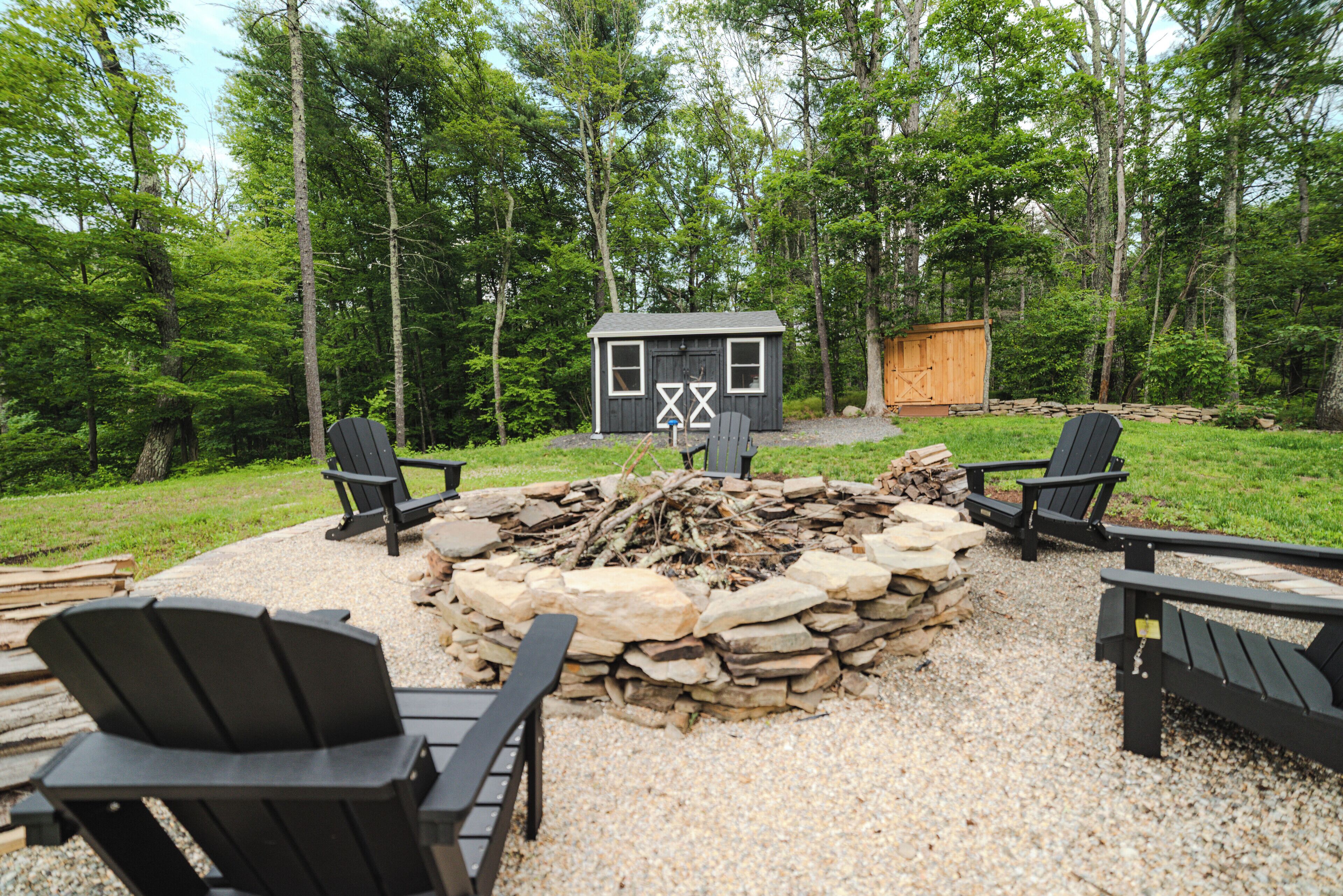 Une cabane avec un foyer en pierre, entourée de fauteuils Adirondack.