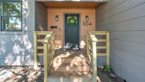 A wooden front door with a number "304" above it, a small porch area, and a wooden staircase leading up to the door.