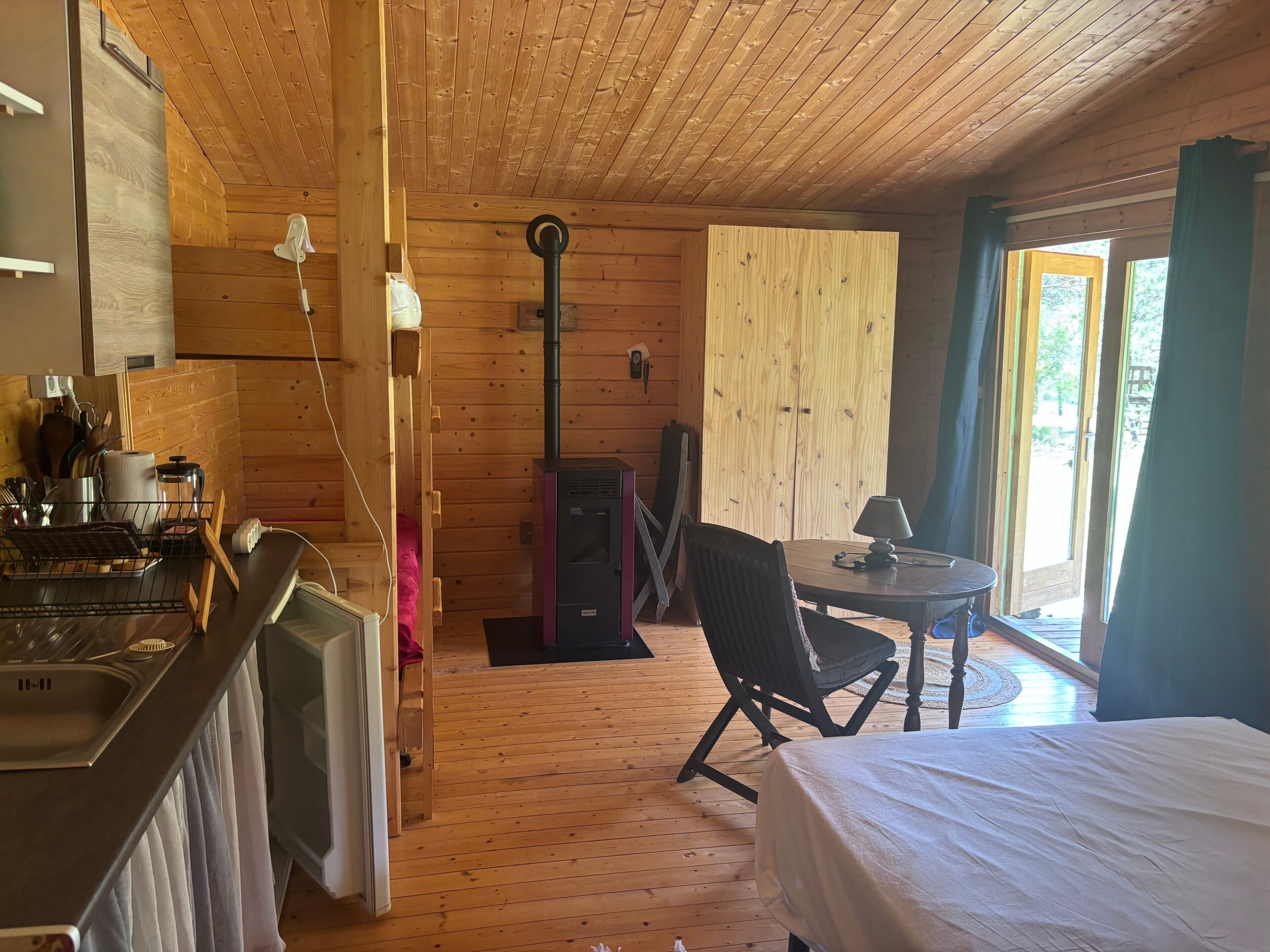 L’intérieur d’une cabine comprend un coin cuisine, une table à manger avec une chaise, un lit et une grande fenêtre.