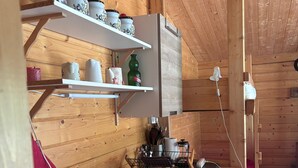 Eine kleine Küche mit Holzwänden, einem eingebauten Spülbecken und Regalen mit Küchenutensilien.